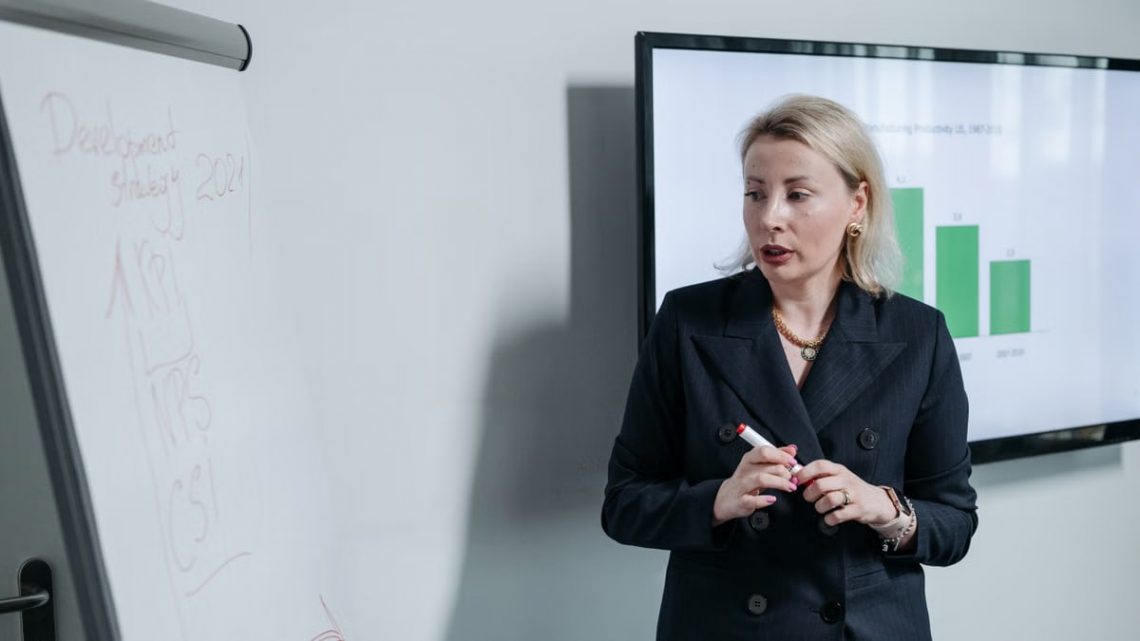 A professional businesswoman presenting a development strategy using charts and graphs in an office setting.