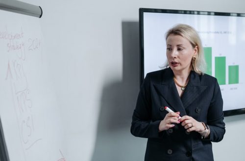 A professional businesswoman presenting a development strategy using charts and graphs in an office setting.